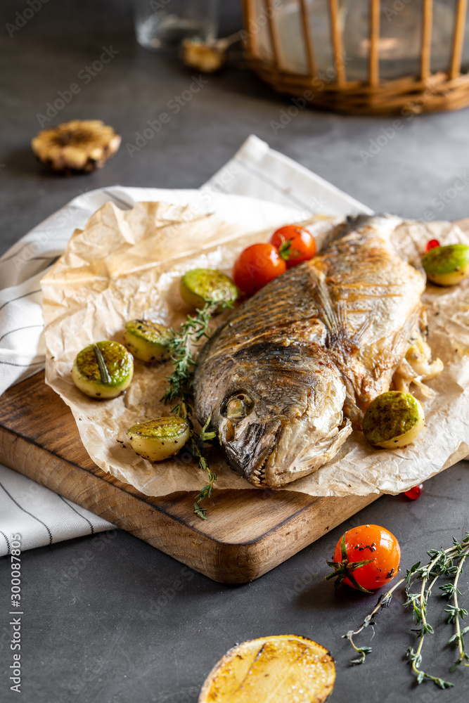 Grilled dorado with vegetables on a dark concrete background. Tasty sea fish. Fish Spar. Grilled dorado with vegetables on a dark concrete background. Tasty sea fish. Fish Spar.