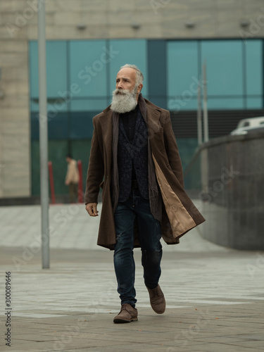 Wallpaper Mural Handsome confident mature man with beard stands in coat on street with copy space for your text message or advertising, fashionable rich male dressed in expensive clothes posing outdoors. Torontodigital.ca