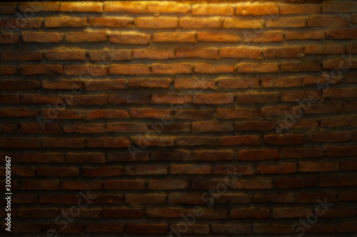 Abstract background of beautiful empty dark brown brick blocks stone wall and warming light from an electric ceiling lamp in the coffee shop. Image taking from a soft focus lens filter.