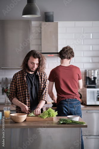 Two friends cook together in the kitchen.