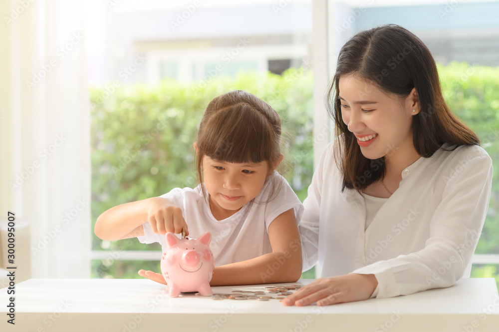 mother help daughter in saving money by collecting coils into piggy bank together mother help daughter in saving money by collecting coils into piggy bank together