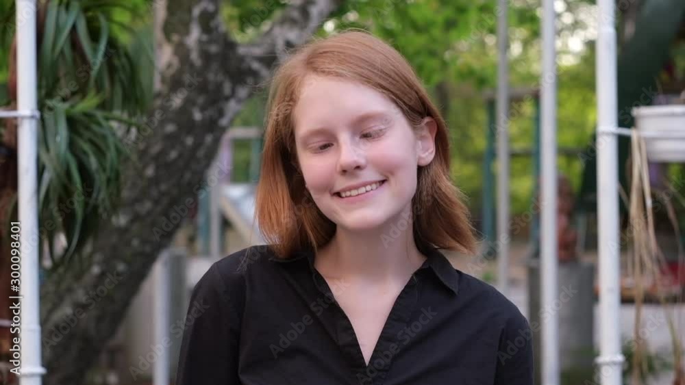 Happy funny ginger woman showing grimaces at camera at city park garden