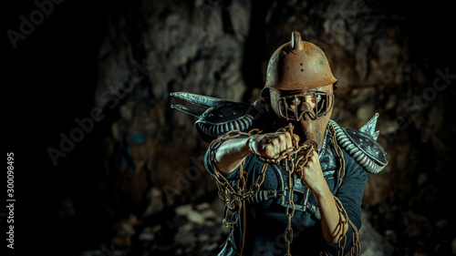 Post-apocalyptic woman in the rusty helmet with a chain in hands on the dungeon background. Nuclear post-apocalypse time. Life after doomsday