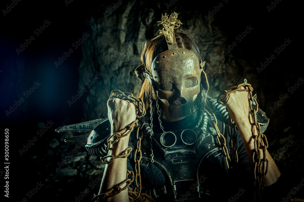 Post-apocalyptic woman in the rusty skull mask on the dungeon background. Nuclear post-apocalypse time. Life after doomsday Post-apocalyptic woman in the rusty skull mask on the dungeon background. Nuclear post-apocalypse time. Life after doomsday