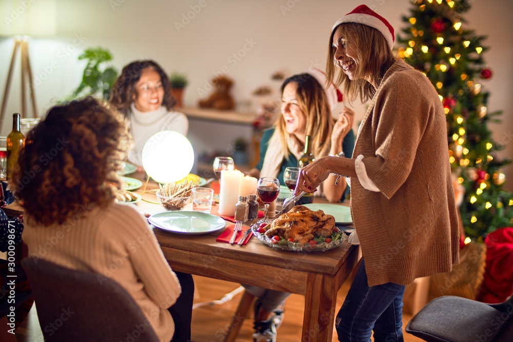 Beautiful group of women smiling happy and confident. Carving roasted turkey celebrating christmas at home