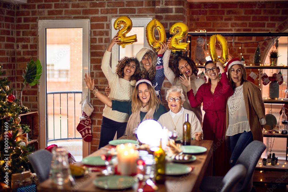 Beautiful group of women smiling happy and confident. Posing around christmas tree holding 2020 ballons at home - obrazy, fototapety, plakaty 
