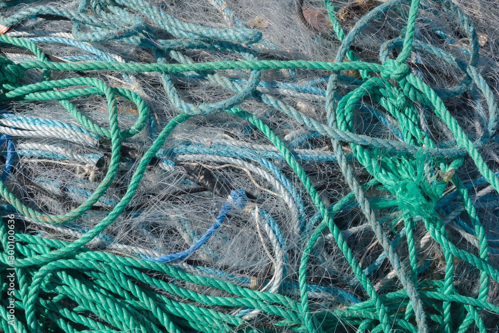 A tangled mess of fishing nets plastic rope and other debris washed up on a coastal beach ideal for an ecological hazard or pollution concept A tangled mess of fishing nets plastic rope and other debris washed up on a coastal beach ideal for an ecological hazard or pollution concept