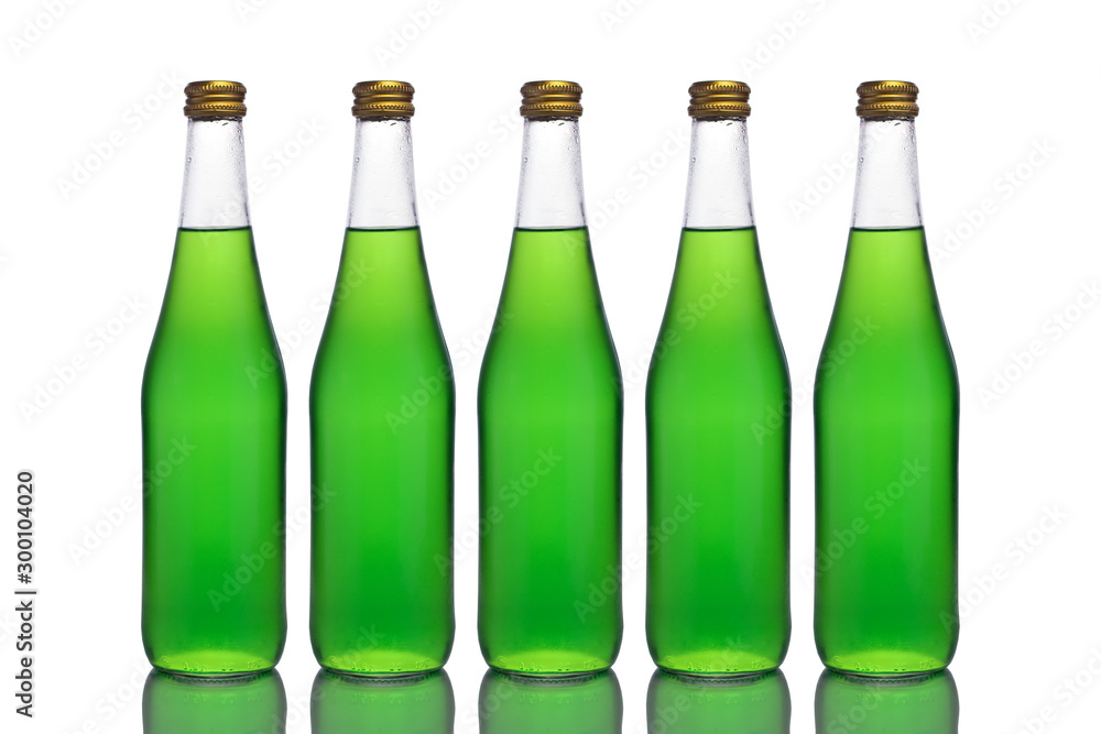 Five large glass bottles with green liquid stand on a mirror surface on a white background in the middle. Five large glass bottles with green liquid stand on a mirror surface on a white background in the middle.