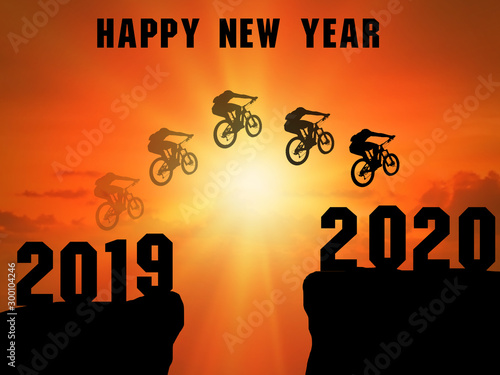 Happy New Year 2020 Silhouette. A young man rode a mountain bike over a cliff. There was a shadow after 2019 to the 2020 cliff. Sunset time photo