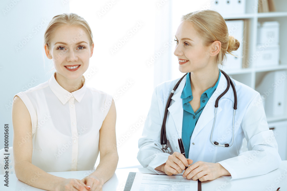 Doctor and patient talking in hospital office while sitting at the desk. Health care and client service in medicine Doctor and patient talking in hospital office while sitting at the desk. Health care and client service in medicine