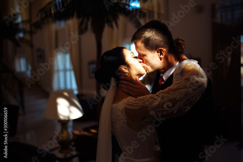 Young married couple in darkness. Newlyweds enjoy each other tenderly. Intimate atmosphere. Luxury elegant wedding couple kissing and embracing. Romantic moment. Together. Wedding.