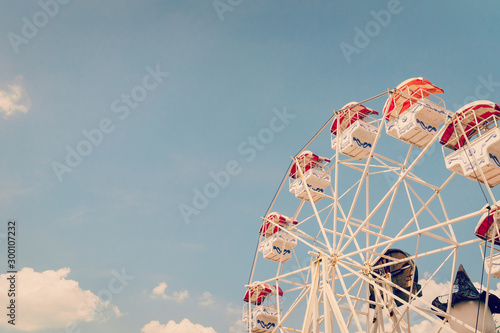 Ferris wheel on cloudy sky background with vintage toned. photo