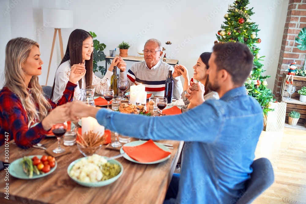 Beautiful family meeting smiling happy and confident. Praying taking hands before eating roasted turkey celebrating Christmas at home Beautiful family meeting smiling happy and confident. Praying taking hands before eating roasted turkey celebrating Christmas at home