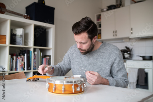 man replacing strings on banjo ukulele photo