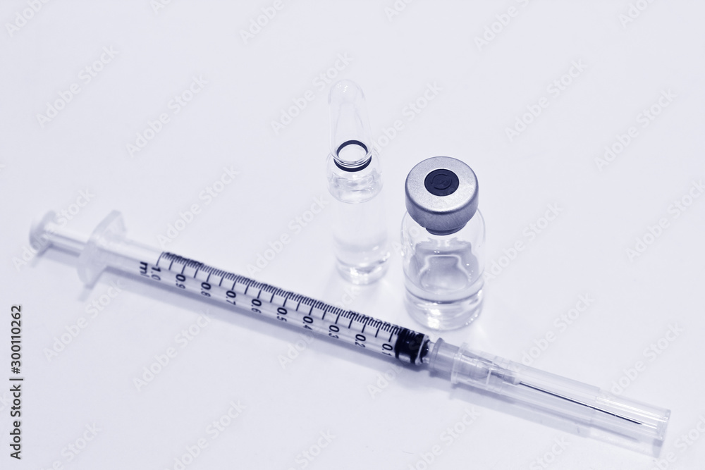 Vial and ampule of drugs or vaccine and 1 ml plastic syringe with needle isolated on the white background, blue tone color Vial and ampule of drugs or vaccine and 1 ml plastic syringe with needle isolated on the white background, blue tone color