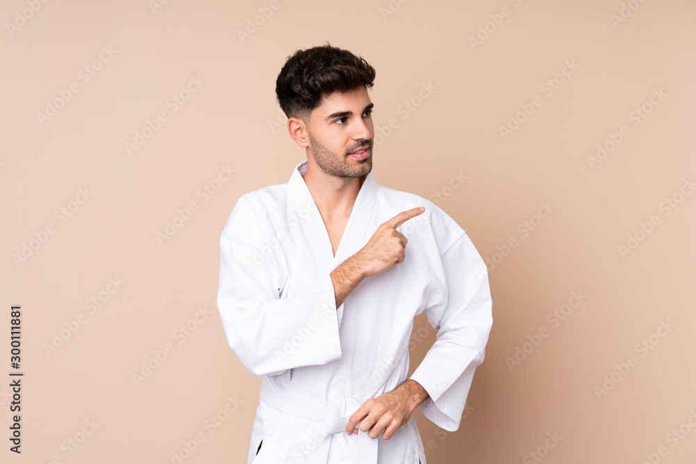 Young man over isolated background doing karate and pointing to the lateral Young man over isolated background doing karate and pointing to the lateral