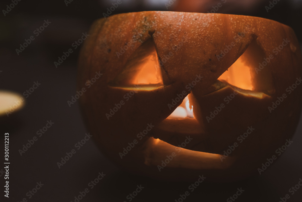 Fototapeta premium Alone head of the pumpkin inside the dark room. Only candle make a light during october halloween night.