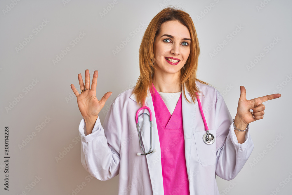 Redhead caucasian doctor woman wearing pink stethoscope over isolated background showing and pointing up with fingers number seven while smiling confident and happy. Redhead caucasian doctor woman wearing pink stethoscope over isolated background showing and pointing up with fingers number seven while smiling confident and happy.
