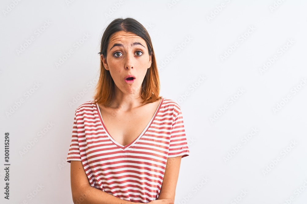 Beautiful redhead woman wearing casual striped red t-shirt over isolated background afraid and shocked with surprise expression, fear and excited face. Beautiful redhead woman wearing casual striped red t-shirt over isolated background afraid and shocked with surprise expression, fear and excited face.