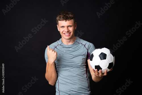 Handsome young football player man over isolated black wall