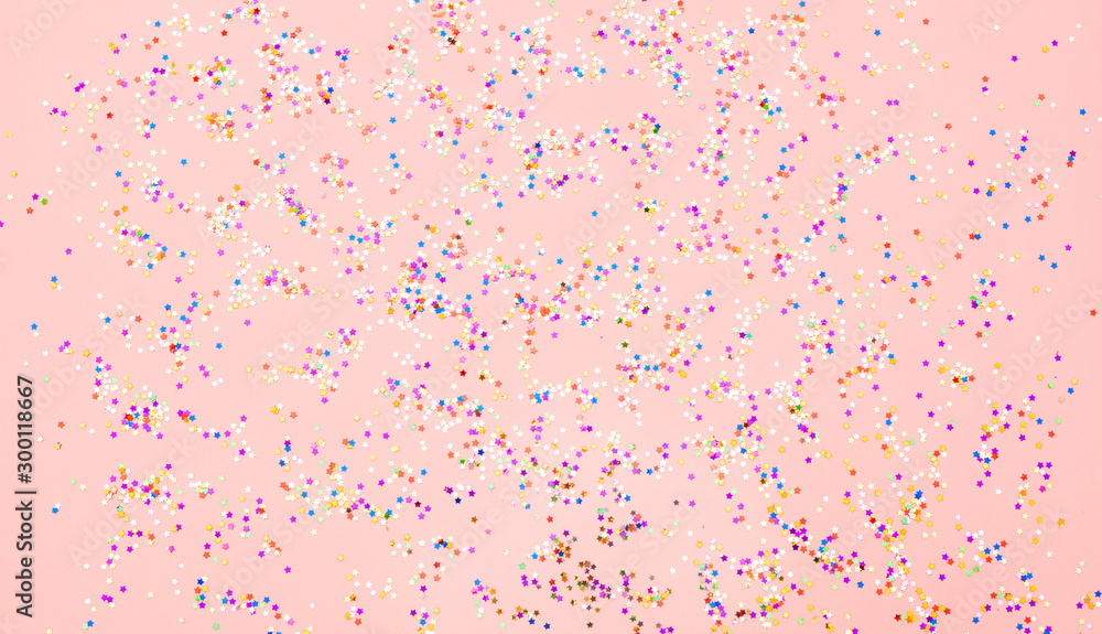 Multicolored confetti glitter on pink background. Holiday abstract backdrop in pastel color Multicolored confetti glitter on pink background. Holiday abstract backdrop in pastel color