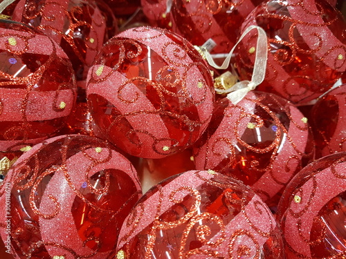 A pile of red glass striped Christmas balls with ornament.