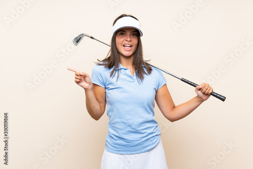 Young golfer woman over isolated background surprised and pointing finger to the side