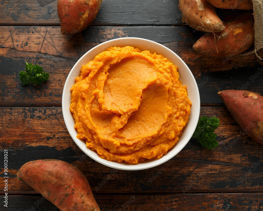 Mashed Sweet Potatoes in white bowl on wooden rustic table. Healthy food - obrazy, fototapety, plakaty 