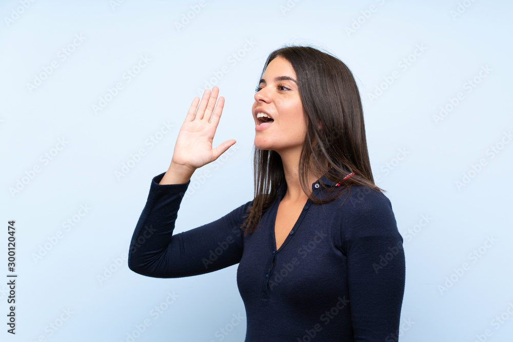 Young girl over isolated blue background shouting with mouth wide open Young girl over isolated blue background shouting with mouth wide open