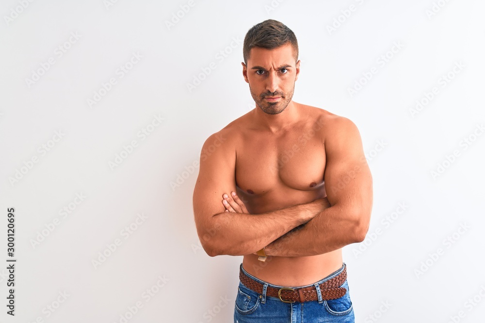 Young handsome shirtless man showing muscular body over isolated background skeptic and nervous, disapproving expression on face with crossed arms. Negative person.