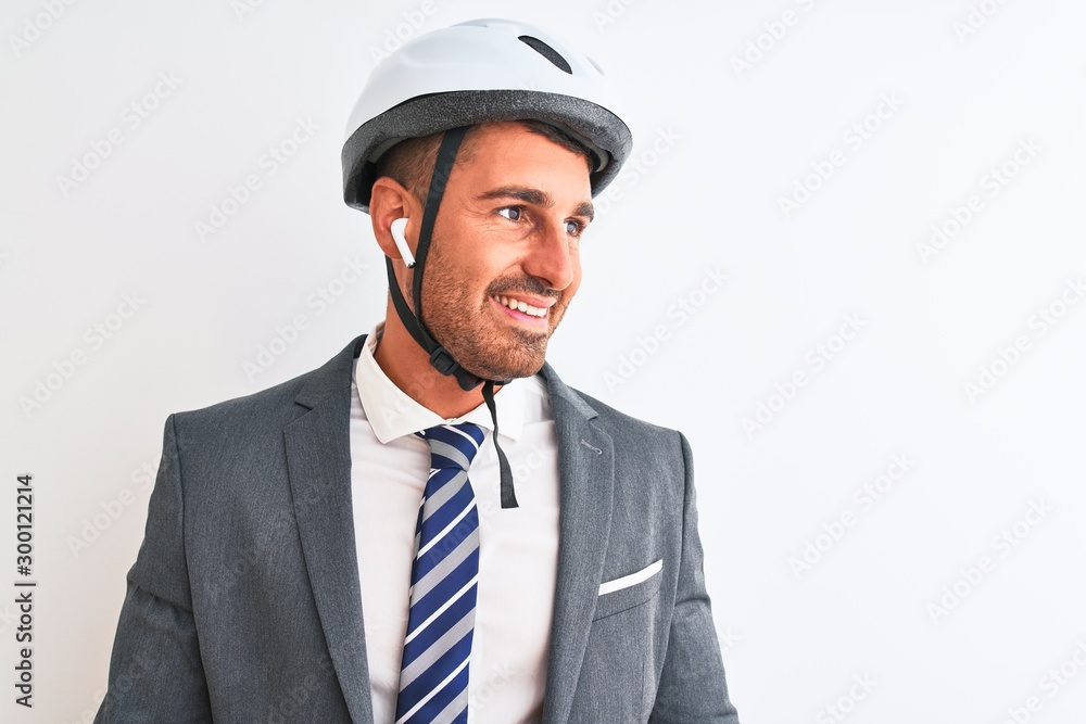 Young handsome business man bike helmet and wireless earphones over isolated background looking away to side with smile on face, natural expression. Laughing confident. Young handsome business man bike helmet and wireless earphones over isolated background looking away to side with smile on face, natural expression. Laughing confident.