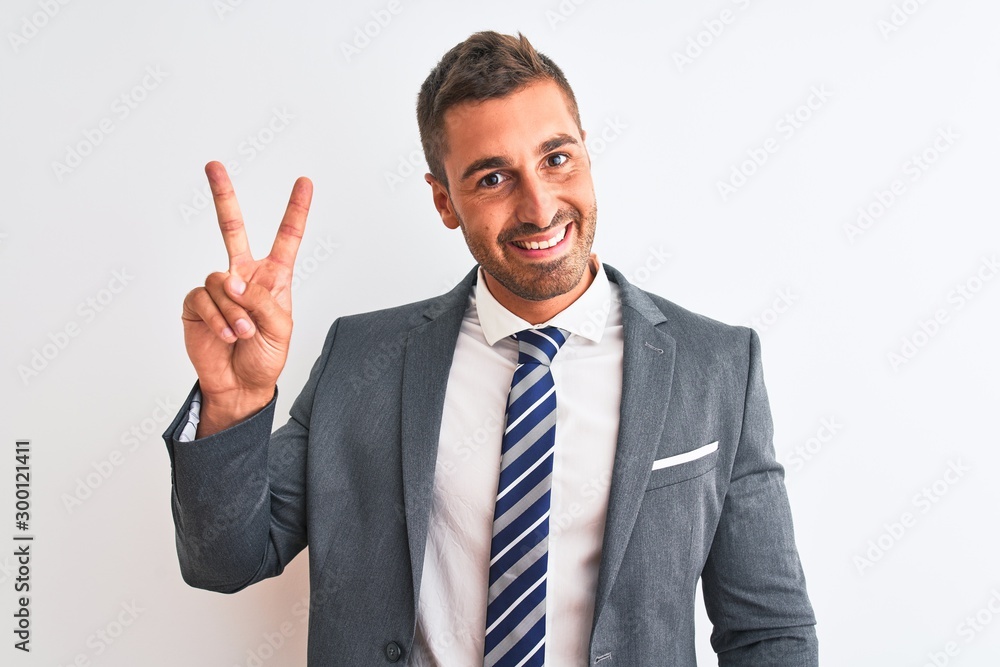 Young handsome business man wearing suit and tie over isolated background smiling looking to the camera showing fingers doing victory sign. Number two. Young handsome business man wearing suit and tie over isolated background smiling looking to the camera showing fingers doing victory sign. Number two.