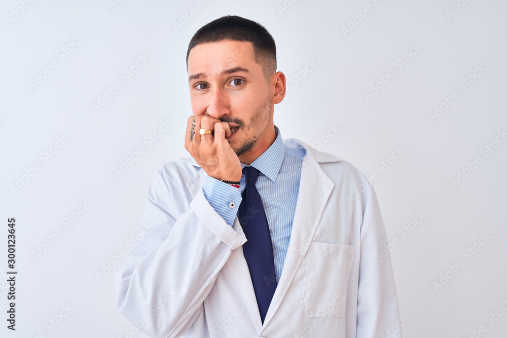 Young doctor man wearing white coat over isolated background looking stressed and nervous with hands on mouth biting nails. Anxiety problem. Young doctor man wearing white coat over isolated background looking stressed and nervous with hands on mouth biting nails. Anxiety problem.
