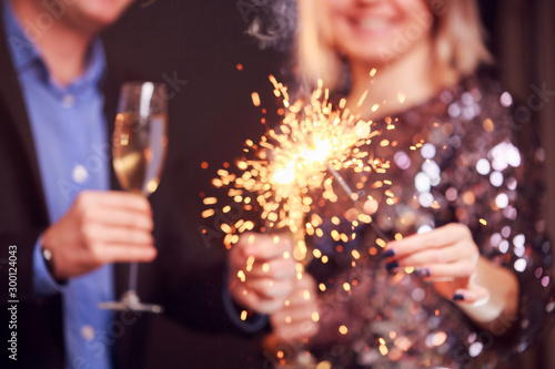 Picture of couple with champagne glasses and sparklers on black background