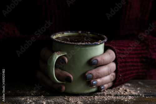 Hands picking up a cup with hot chocolate