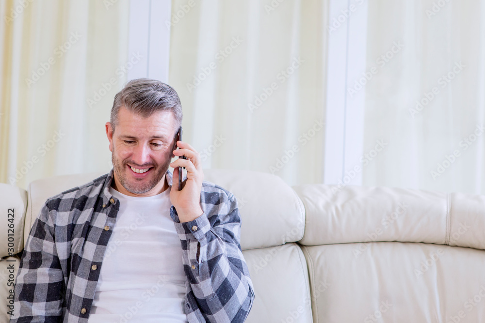 Man looks happy while talking on a phone at home