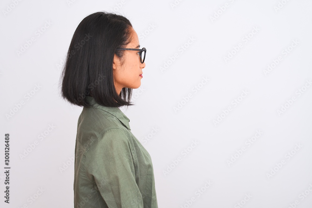 Young chinese woman wearing green shirt and glasses over isolated white background looking to side, relax profile pose with natural face with confident smile. Young chinese woman wearing green shirt and glasses over isolated white background looking to side, relax profile pose with natural face with confident smile.
