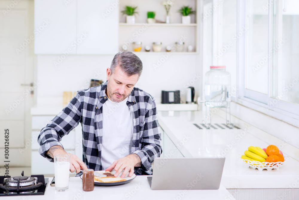 Mature man making breakfast while working Mature man making breakfast while working