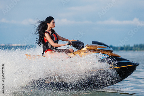 Obraz na plátně Athletic brunette rides a jet ski at sea