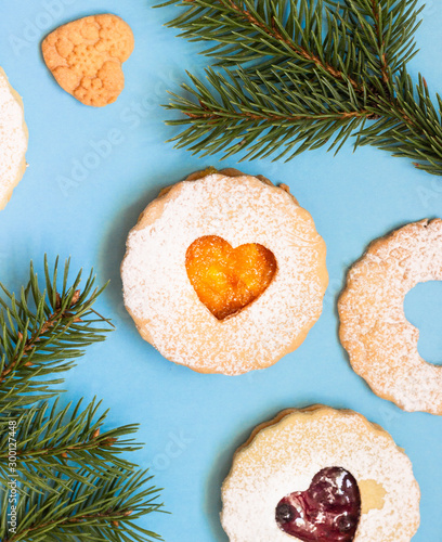 Linzer Christmas or New Year cookies filled with jam and dusted with sugar on blue paper background. Traditional Austrian Christmas cookies. Festive decoration.