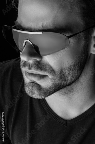 Black and White Muscle strong beautiful stripped male model with white black t-shirt and glasses eyewear on black isolated font background