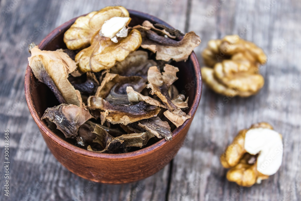 Walnut kernels and partitions in a bowl and whole walnuts on a wooden table. A medicine for tinctures and decoctions. Walnut kernels and partitions in a bowl and whole walnuts on a wooden table. A medicine for tinctures and decoctions.