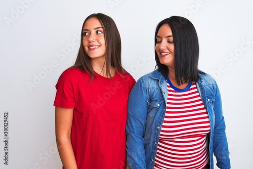 Young beautiful women wearing casual clothes standing over isolated white background looking away to side with smile on face, natural expression. Laughing confident.