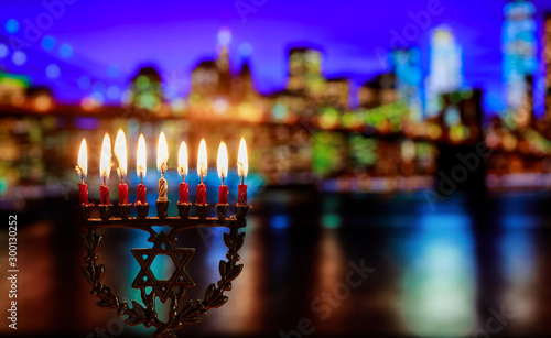 Hanukkah menorah symbol of Jewish traditional holiday Brooklyn Bridge over night New York City with lights