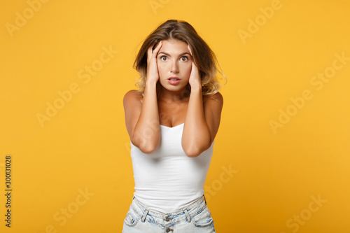 Shocked young woman in light casual clothes posing isolated on yellow orange wall background, studio portrait. People sincere emotions lifestyle concept. Mock up copy space. Putting hands on head.
