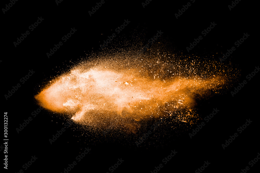 Abstract orange powder explosion on black background. Freeze motion of ...