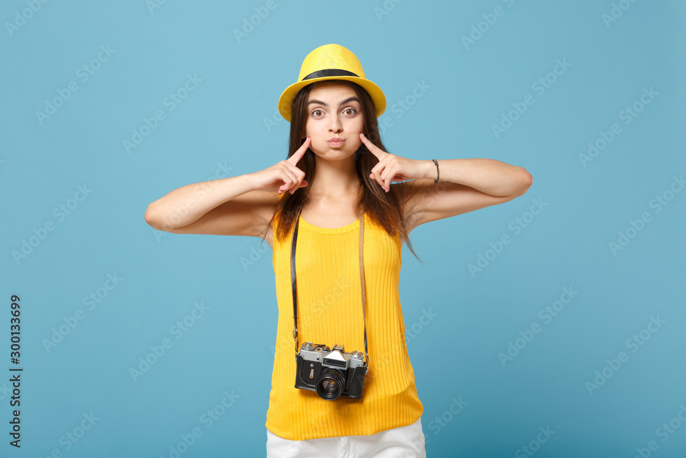 Traveler tourist woman in yellow summer casual clothes, hat with photo camera isolated on blue background. Female passenger traveling abroad to travel on weekends getaway. Air flight journey concept.