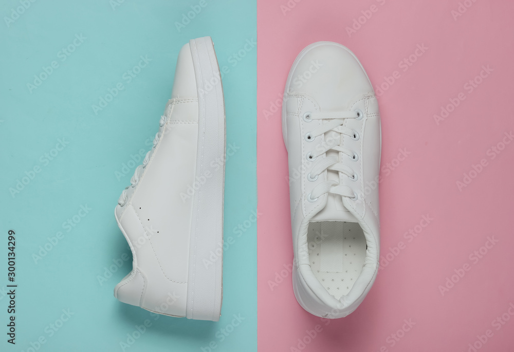 Stylish white sneakers on pink blue pastel background. Top view Stylish white sneakers on pink blue pastel background. Top view