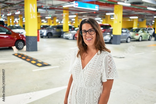 Young woman smiling confident at underground parking lot around cars and lights