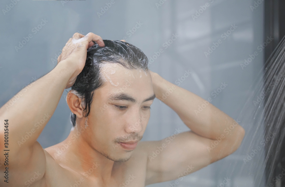 Fototapeta premium Closeup young man washing hair with with shampoo in the bathroom, vintage tone, selective focus
